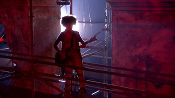 Movie still from “Jesus Christ Superstar Live in Concert” (2018), directed by Alex Rudzinski – A person with a guitar standing in a room; Wide shot, Low angle