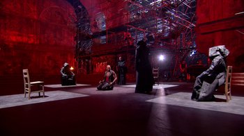 Movie still from “Jesus Christ Superstar Live in Concert” (2018), directed by Alex Rudzinski – A group of people sitting on the ground in a room; Extreme Wide shot, High angle