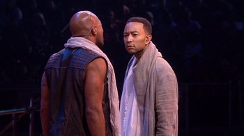 Movie still from “Jesus Christ Superstar Live in Concert” (2018), directed by Alex Rudzinski – Two men standing next to each other on a stage; Medium shot, Over the shoulder angle