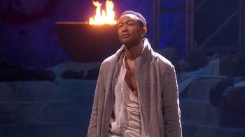 Movie still from “Jesus Christ Superstar Live in Concert” (2018), directed by Alex Rudzinski – A man standing in front of a fire pit; Medium shot, Low angle