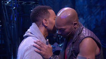 Movie still from “Jesus Christ Superstar Live in Concert” (2018), directed by Alex Rudzinski – A couple of people that are kissing in a room; Medium shot, Over the shoulder angle