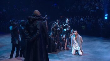 Movie still from “Jesus Christ Superstar Live in Concert” (2018), directed by Alex Rudzinski – A group of people sitting and standing on a stage; Wide shot, High angle
