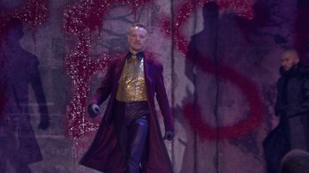 Movie still from “Jesus Christ Superstar Live in Concert” (2018), directed by Alex Rudzinski – A man in a purple coat and a gold shirt; Wide shot, Low angle