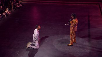Movie still from “Jesus Christ Superstar Live in Concert” (2018), directed by Alex Rudzinski – A man kneeling on the ground in front of another man; Extreme Wide shot, High angle