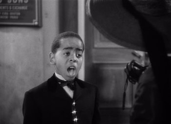 Movie still from “Jezebel” (1938), directed by William Wyler – A black and white photo of a young man in a suit and bow tie; Close Up shot, High angle