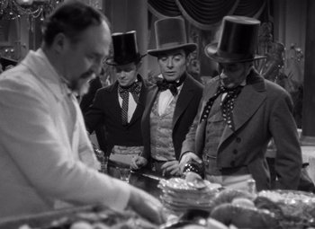 Movie still from “Jezebel” (1938), directed by William Wyler – A group of men in top hats and ties cutting cake; Medium shot, Over the shoulder angle
