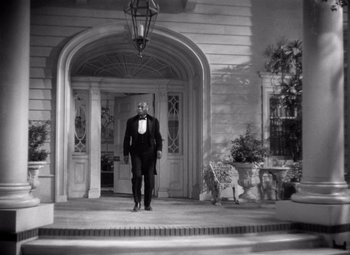 Movie still from “Jezebel” (1938), directed by William Wyler – A man standing in front of an entrance to a house; Wide shot, Low angle