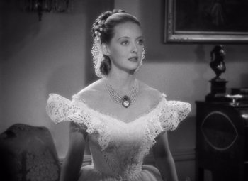 Movie still from “Jezebel” (1938), directed by William Wyler – A black and white photo of a woman in a dress; Close Up shot, Over the shoulder angle