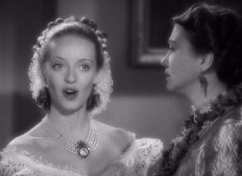 Movie still from “Jezebel” (1938), directed by William Wyler – Two women are talking to each other in a black and white photo; Close Up shot, Over the shoulder angle
