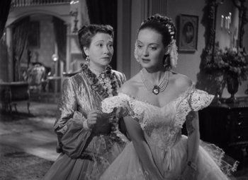 Movie still from “Jezebel” (1938), directed by William Wyler – Two women dressed in old - fashioned clothing in a room; Medium shot, Over the shoulder angle