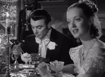 Movie still from “Jezebel” (1938), directed by William Wyler – A man and a woman sitting at a dinner table; Medium shot, High angle