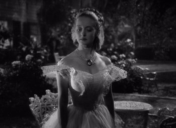 Movie still from “Jezebel” (1938), directed by William Wyler – A black and white photo of a woman in a dress; Medium shot, Low angle
