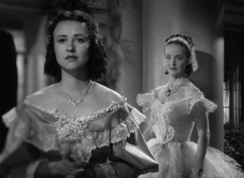 Movie still from “Jezebel” (1938), directed by William Wyler – Two young women in old - fashioned dresses posing for a picture; Close Up shot, Over the shoulder angle