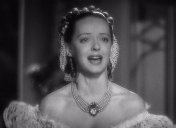 Movie still from “Jezebel” (1938), directed by William Wyler – A black and white photo of a woman wearing a necklace; Close Up shot, Low angle