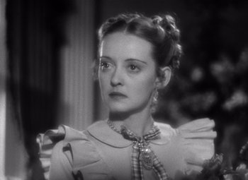 Movie still from “Jezebel” (1938), directed by William Wyler – A black and white photo of a woman in a dress; Close Up shot, High angle