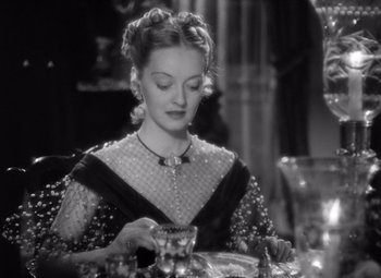 Movie still from “Jezebel” (1938), directed by William Wyler – A woman sitting at a table with a glass of wine; Close Up shot, High angle