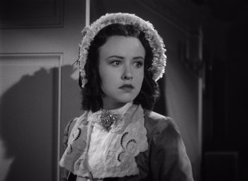 Movie still from “Jezebel” (1938), directed by William Wyler – A young woman in an old fashioned dress and a hat; Close Up shot, High angle