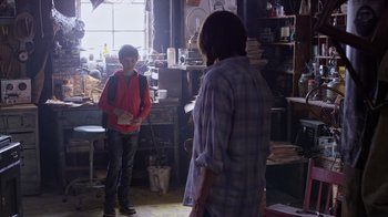 Movie still from “Turkey Hollow” (2015), directed by Kirk R. Thatcher – Two young people standing in a cluttered room; Wide shot, Over the shoulder angle