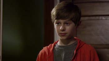 Movie still from “Turkey Hollow” (2015), directed by Kirk R. Thatcher – A boy in a red jacket is looking at the camera; Close Up shot, Over the shoulder angle