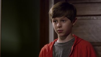 Movie still from “Turkey Hollow” (2015), directed by Kirk R. Thatcher – A young boy wearing a gray shirt and a red jacket; Close Up shot, Over the shoulder angle