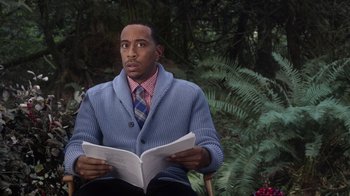 Movie still from “Turkey Hollow” (2015), directed by Kirk R. Thatcher – A man sitting in a chair reading a book; Close Up shot, Over the shoulder angle