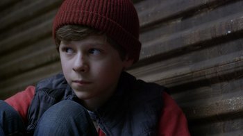 Movie still from “Turkey Hollow” (2015), directed by Kirk R. Thatcher – A young boy wearing a red hat and jacket; Close Up shot, High angle