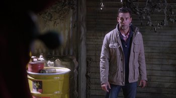 Movie still from “Turkey Hollow” (2015), directed by Kirk R. Thatcher – A man standing in front of a yellow barrel; Medium shot, Over the shoulder angle
