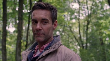 Movie still from “Turkey Hollow” (2015), directed by Kirk R. Thatcher – A person wearing a jacket in the woods; Close Up shot, Over the shoulder angle