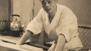 Movie still from “Jiro Dreams of Sushi” (2011), directed by David Gelb – A man sitting at a table in a room; Close Up shot, Low angle