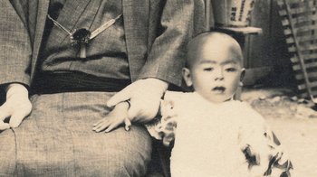 Movie still from “Jiro Dreams of Sushi” (2011), directed by David Gelb – An old photo of a man holding a baby; Extreme Close Up shot, Overhead angle