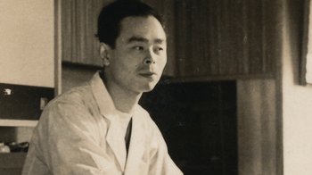 Movie still from “Jiro Dreams of Sushi” (2011), directed by David Gelb – An old black and white photo of a man wearing a tie; Extreme Close Up shot, Low angle