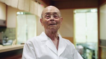 Movie still from “Jiro Dreams of Sushi” (2011), directed by David Gelb – An older man wearing glasses and a white shirt; Close Up shot, Low angle