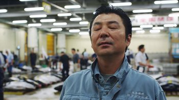 Movie still from “Jiro Dreams of Sushi” (2011), directed by David Gelb – A man with his eyes closed in an airport terminal; Close Up shot, Low angle
