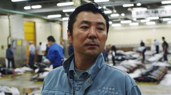 Movie still from “Jiro Dreams of Sushi” (2011), directed by David Gelb – A man standing in front of a room filled with people; Close Up shot, Low angle