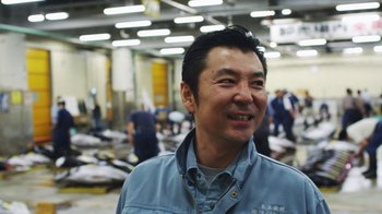 Movie still from “Jiro Dreams of Sushi” (2011), directed by David Gelb – A man standing in front of a room filled with fish; Medium shot, Low angle