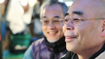 Movie still from “Jiro Dreams of Sushi” (2011), directed by David Gelb – A man and a woman wearing glasses and smiling; Close Up shot, Low angle