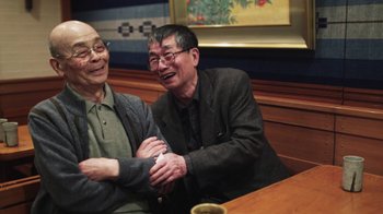 Movie still from “Jiro Dreams of Sushi” (2011), directed by David Gelb – Two older men sitting next to each other at a table; Medium shot, High angle