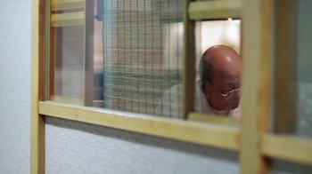 Movie still from “Jiro Dreams of Sushi” (2011), directed by David Gelb – An older man sitting in front of a window; Medium shot, Low angle