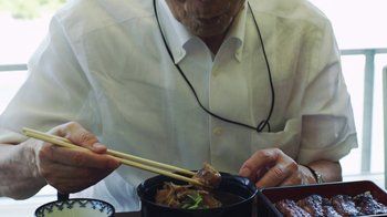 Movie still from “Jiro Dreams of Sushi” (2011), directed by David Gelb – An older man holding chopsticks over a bowl of food; Close Up shot, High angle