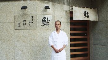 Movie still from “Jiro Dreams of Sushi” (2011), directed by David Gelb – A man standing in front of a stone wall; Medium shot, Low angle