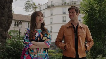 Movie still from “Emily in Paris” (2020), created by Darren Star – A man and a woman standing next to each other in front of a building; Medium shot, Over the shoulder angle