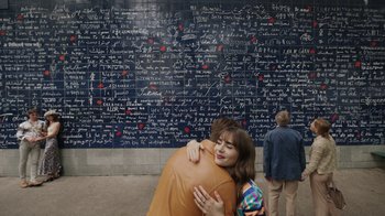 Movie still from “Emily in Paris” (2020), created by Darren Star – A woman hugging a man in front of a wall covered in writing; Wide shot, Overhead angle