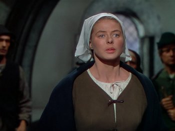 Movie still from “Joan of Arc” (1948), directed by Victor Fleming – A woman wearing a head scarf and a brown dress; Medium shot, Low angle