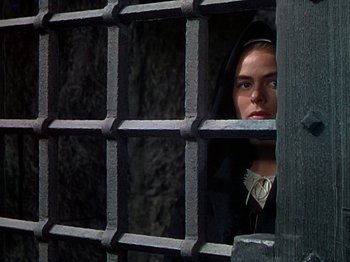 Movie still from “Joan of Arc” (1948), directed by Victor Fleming – A woman in a hooded jacket looking out a window; Close Up shot, Over the shoulder angle