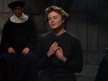 Movie still from “Joan of Arc” (1948), directed by Victor Fleming – A woman in a black shirt is holding her hands together; Medium shot, Over the shoulder angle