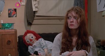 Movie still from “Joe” (1970), directed by John G. Avildsen – A woman sitting on a couch next to a rag doll; Close Up shot, Over the shoulder angle