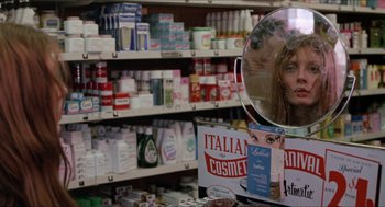 Movie still from “Joe” (1970), directed by John G. Avildsen – A woman's reflection in a mirror in a cosmetics store; Close Up shot, Over the shoulder angle