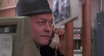 Movie still from “Joe” (1970), directed by John G. Avildsen – A man in a hat is talking on a phone; Close Up shot, Low angle