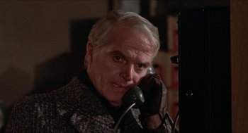 Movie still from “Joe” (1970), directed by John G. Avildsen – An older man talking on a phone while wearing gloves; Close Up shot, Low angle