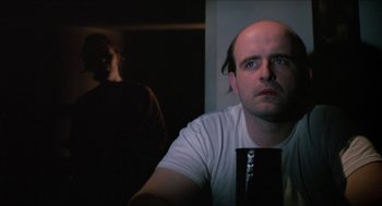 Movie still from “Joe” (1970), directed by John G. Avildsen – A man with a bald head is looking at the camera; Close Up shot, Over the shoulder angle